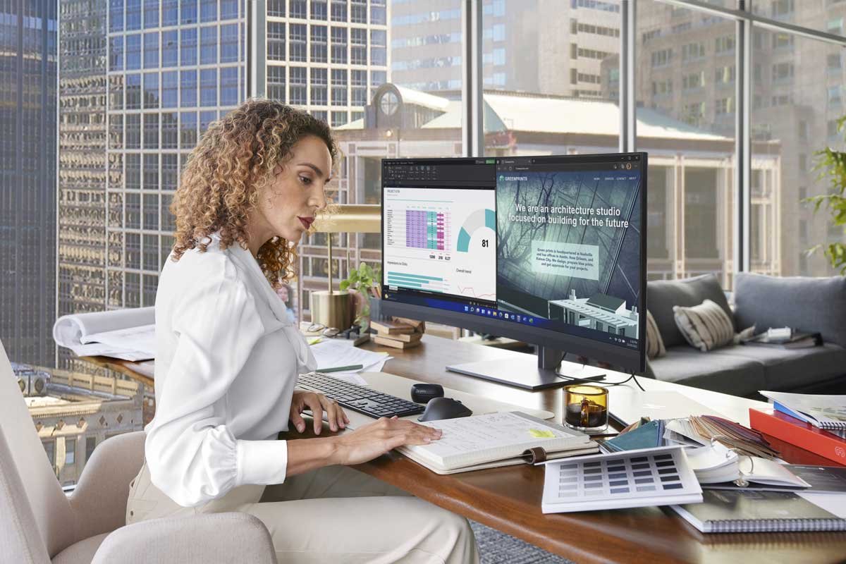 Woman working on a curved monitor in an office setting.